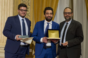  Cesare Giuzzi del Gruppo cronisti e l'assessore comunale Marco Granelli consegnano la targa per il secondo premio a Giambattista Anastasio del Giorno” height=